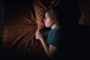 Woman laying in bed on rust-colored bed sheets