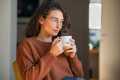 Woman in a brown sweater sitting and drinking coffee