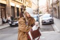 Woman searching through her bag on a city street, distracted and unfocused