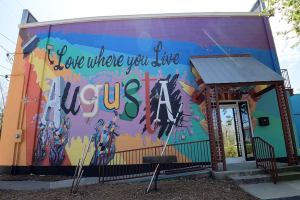 A mural outside on the side of a building that says "Love where you live" and "Augusta"