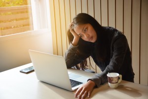 Woman sitting in front of laptop looking anxious