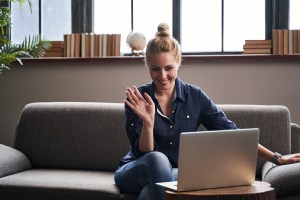 Woman in virtual psychiatry intake session, waving at the laptop screen