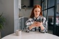 Woman sitting at a table texting someone with a serious look on her face