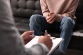 Close up of man's hands clasped as he sits in a chair across from a therapist